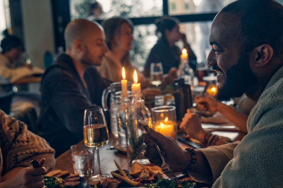 invités profitant d'un bon repas autours d'une table illuminée par des chandelles au restaurant