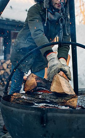 artisan adding wood to an outdoor fire