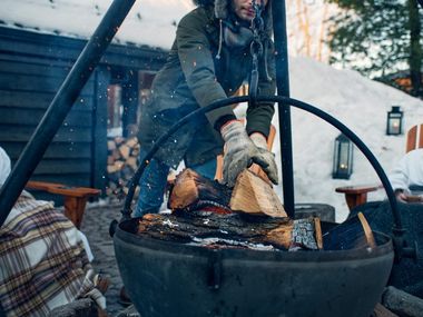 artisan adding wood to an outdoor fire