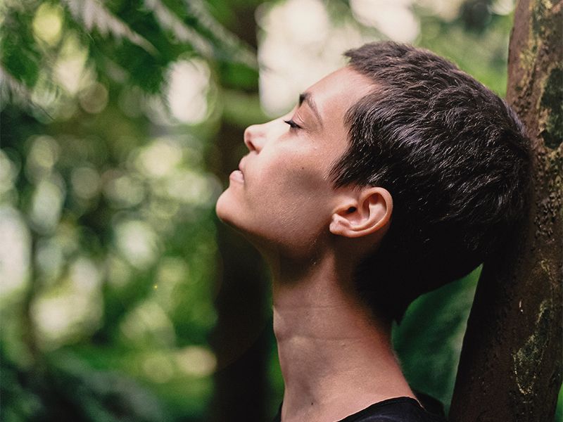 woman breathing while surrounded by trees