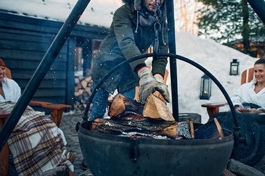 artisan adding wood to an outdoor fire
