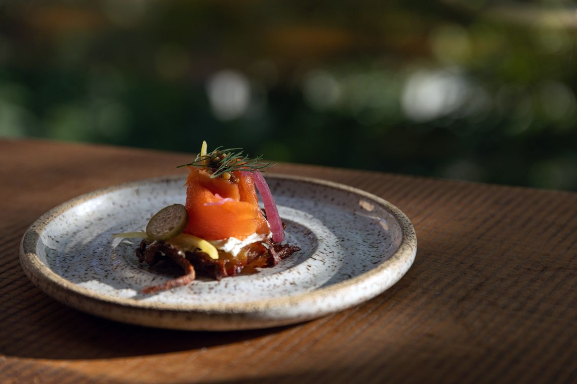 cracker topped with salmon gravlax, Dijon mustard, capers, and pickled onions