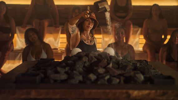 Artisan de rituel versant de l'eau sur des pierres chaudes