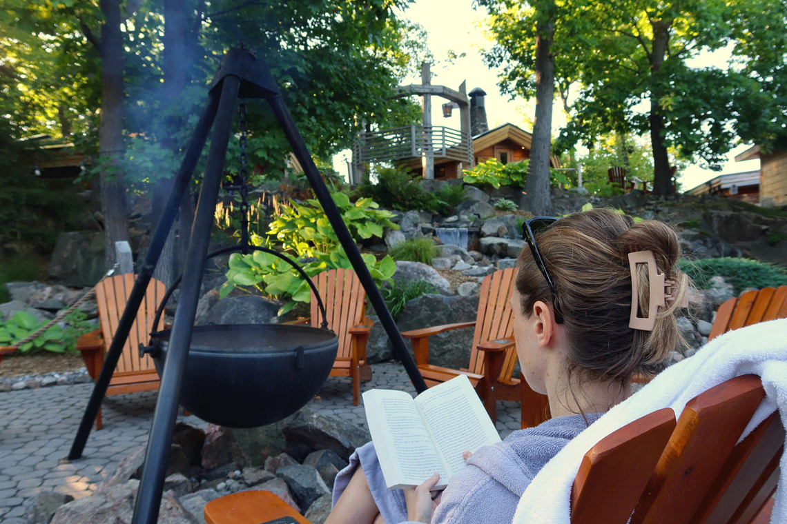Emily reading a book by a fire cauldron