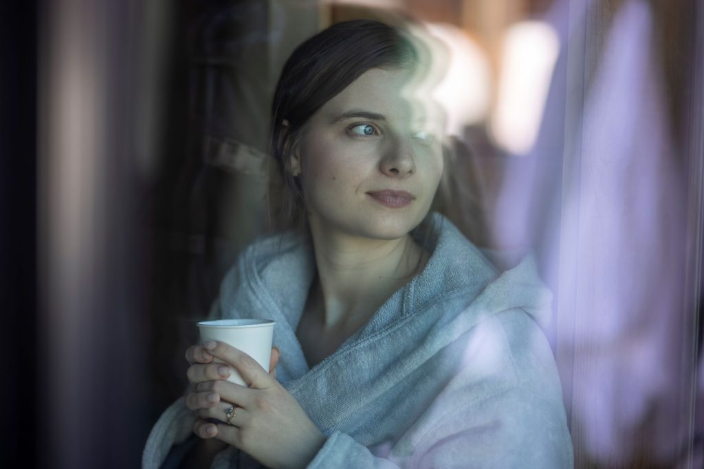 woman takes a moment to reflect in silence while holding a comforting beverage
